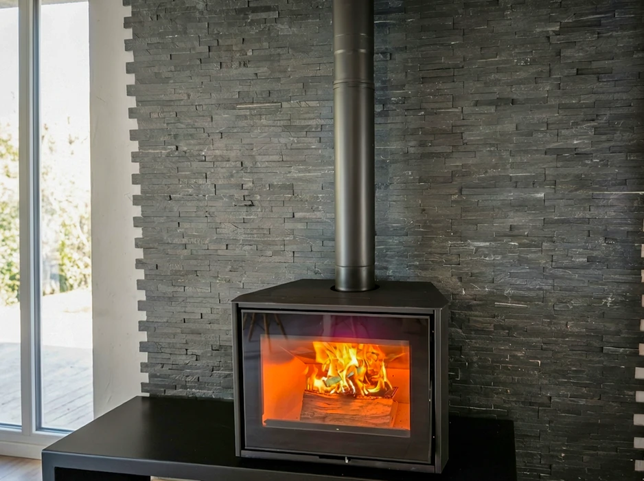 Intérieur moderne avec un poêle à bois freestanding noir, vitré sur façade, produisant une flamme vive orangée